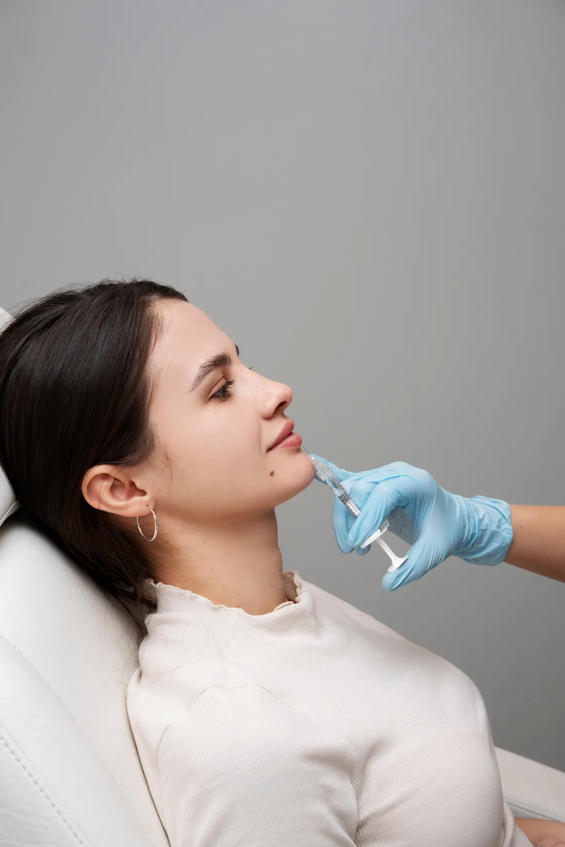 Patient reclined receiving an injectable treatment to the lower face from a gloved practitioner